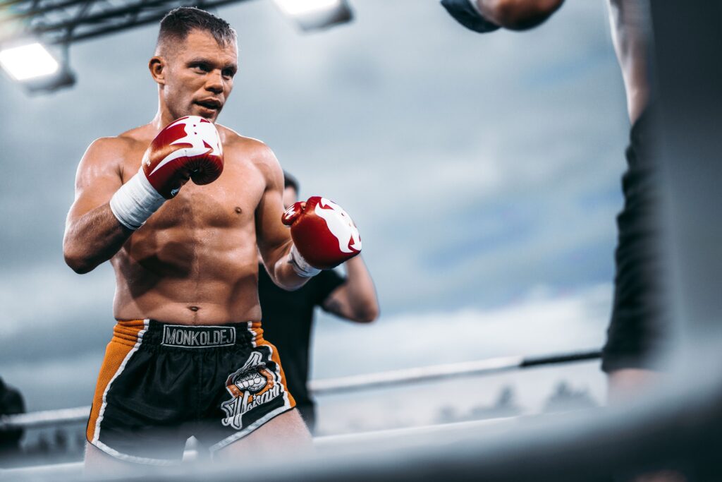 Focused boxer in action at outdoor match, showcasing strength and determination.